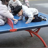 两个小男孩找小女孩要可乐，没地方倒直接倒在乒乓球台上，小男孩喝得意犹未尽