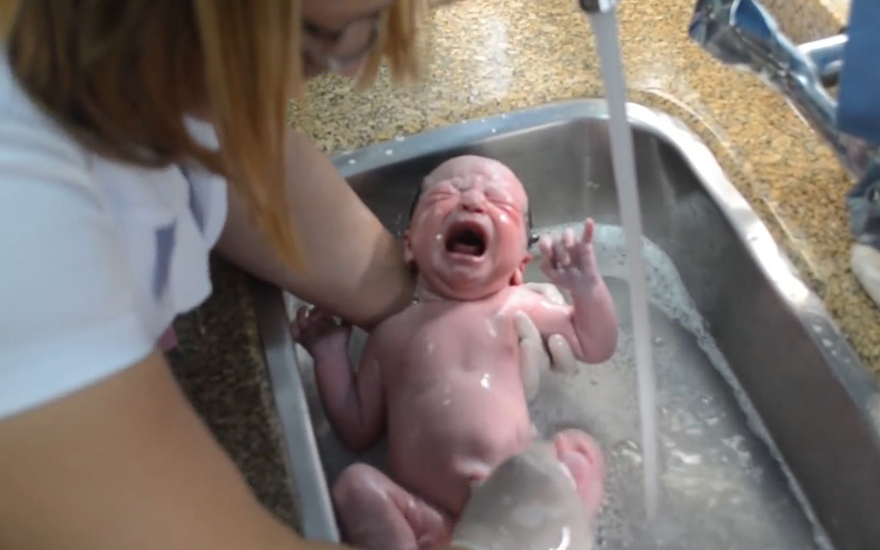 护士将新生儿放在水龙头下冲洗，手法随意粗鲁，像洗萝卜一样