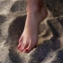 女孩光着脚在沙滩上行走，脚底一沾到沙子，就会被沙滩吃掉！