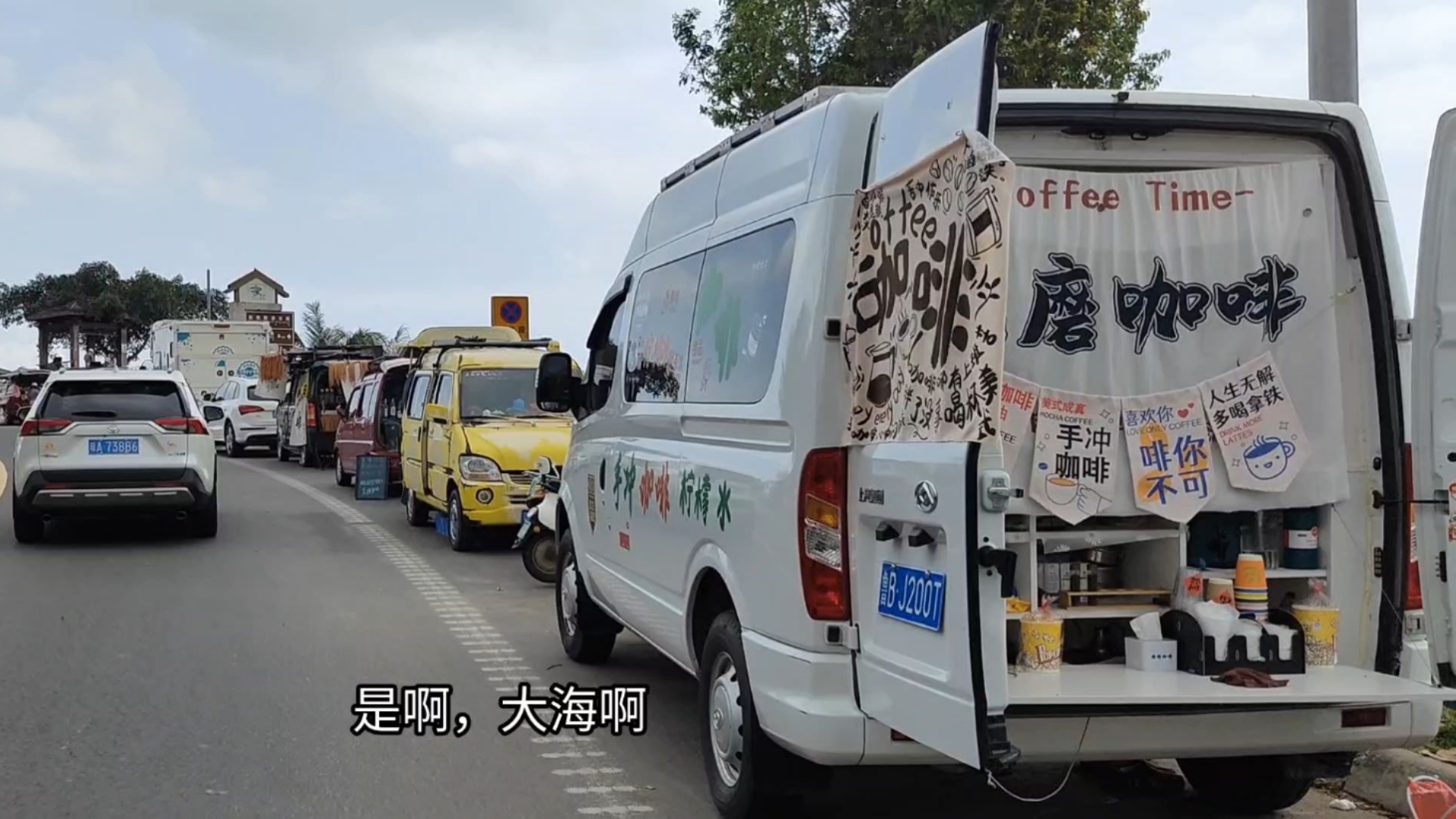 万宁石梅湾观海亭，人多车多，道路两边全是咖啡车，海边有很多冲浪的年轻人。