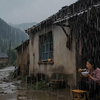 落后的大山沟，大雨天搬个板凳，坐在门口屋檐下，边吃饭，边看着门口的大雨，庆幸今天下大雨，不用下地干农活