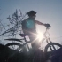 一个骑自行车的人在太阳前的剪影，在自然界的草地上慢慢地走着高清视频素材