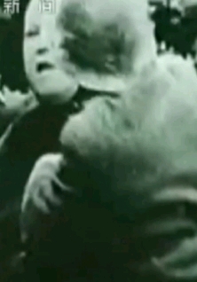 镜头三:两个日本兵挥舞着手里的刺刀抢夺中国平民手里的粮袋.