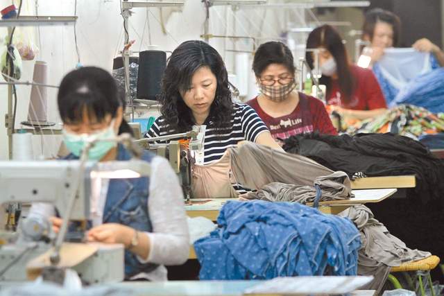 图为成衣加工厂员工正在车缝服饰.
