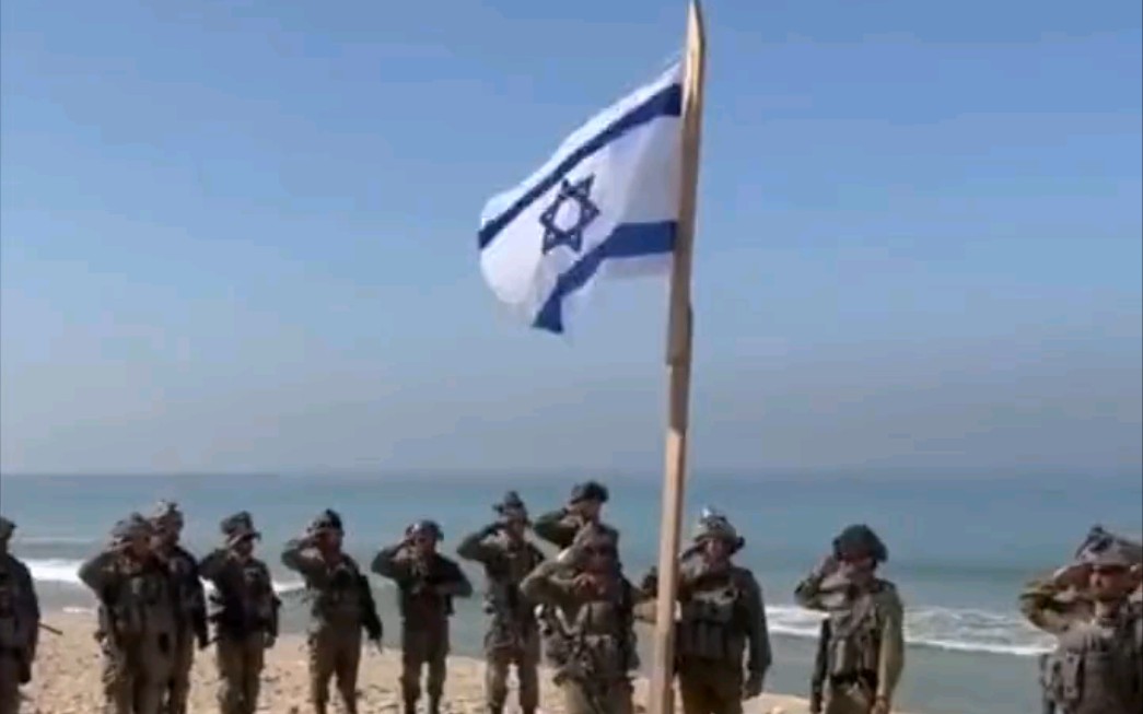 以色列军队在加沙的一个海滩上举起以色列国旗,唱着以色列国歌
