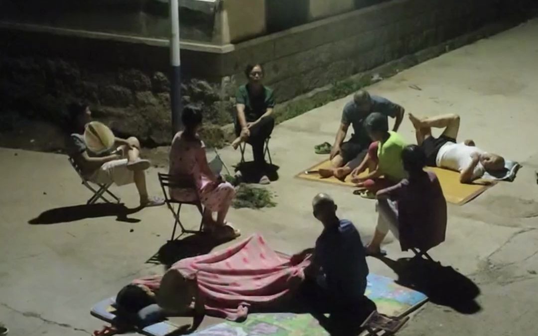7月27日,山东烟台,晚饭后,街坊邻居围坐在路灯下乘凉,好不惬意!