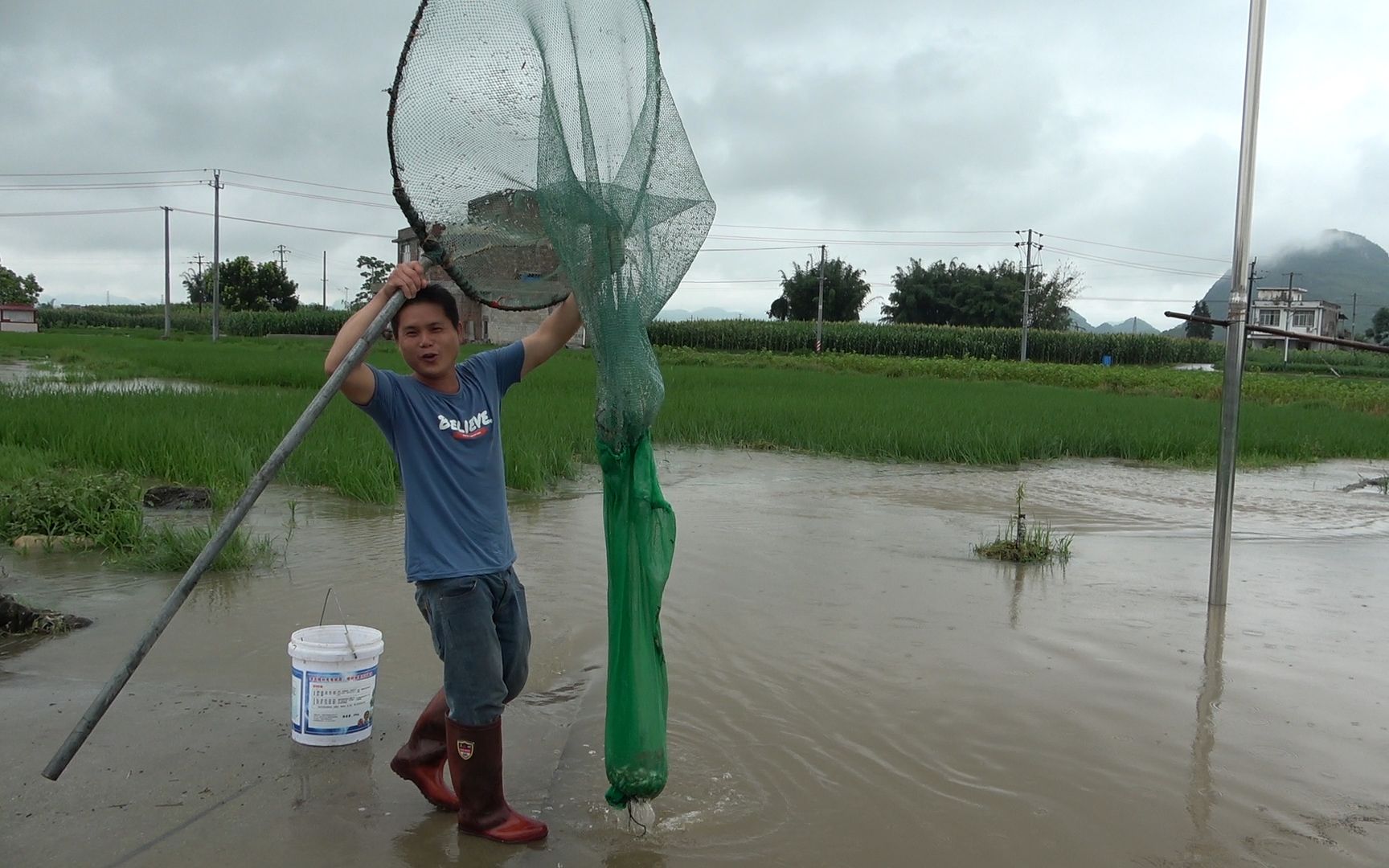 一夜暴雨河水猛涨小伙用4米长大抄网,在拱桥下拦鱼收获太惊喜了
