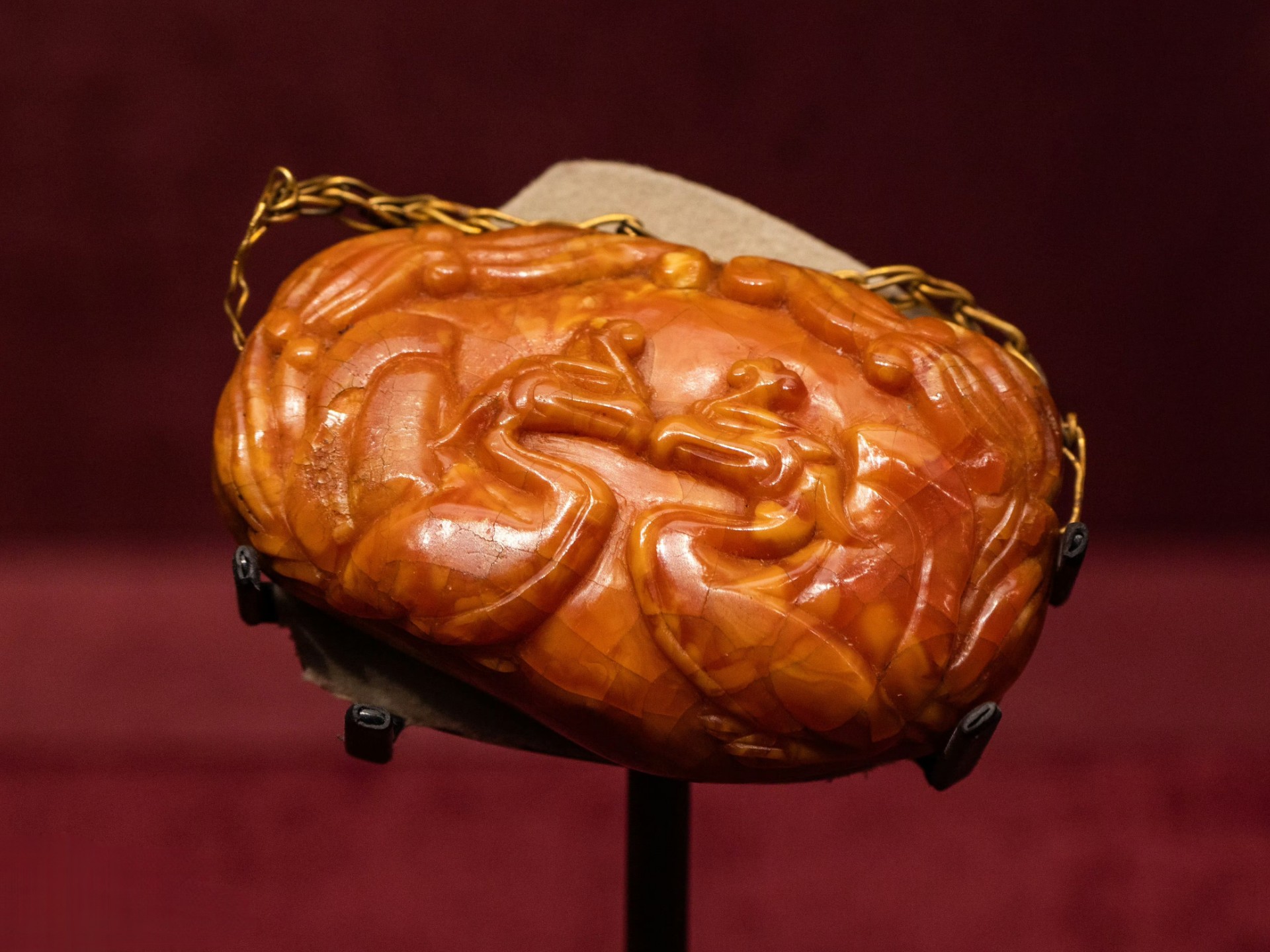 内蒙古文物考古研究所,有件辽代双凤纹琥珀握手,橘红色,椭圆形,出土于