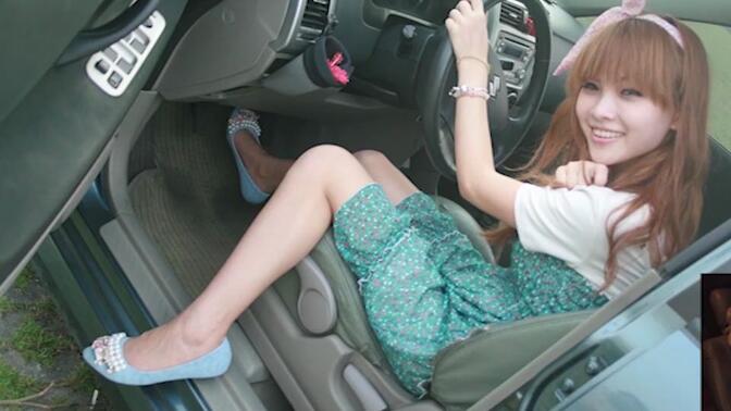 个美丽的亚洲女性穿着平底鞋,轰油门驾驶她的车pedalpumping踩油门