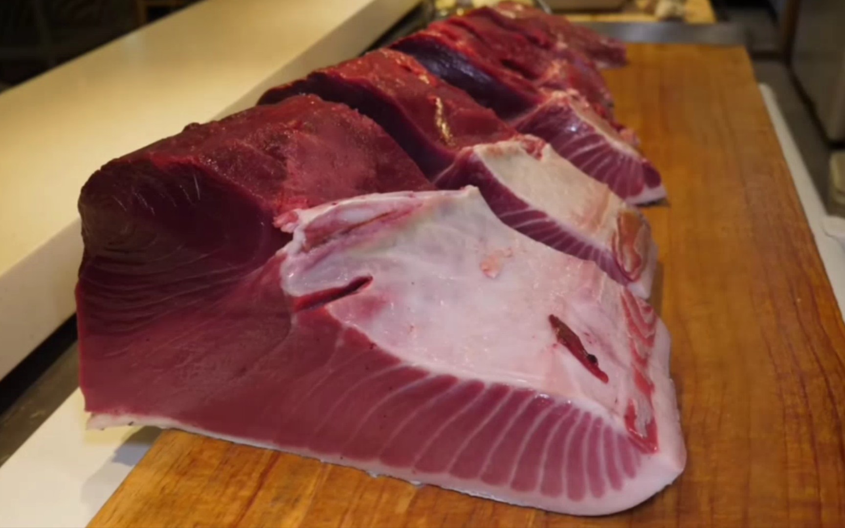 超大金枪鱼在主厨的长刀下,根据不同部位分成多块,有鱼头,鱼鳍,鱼肉