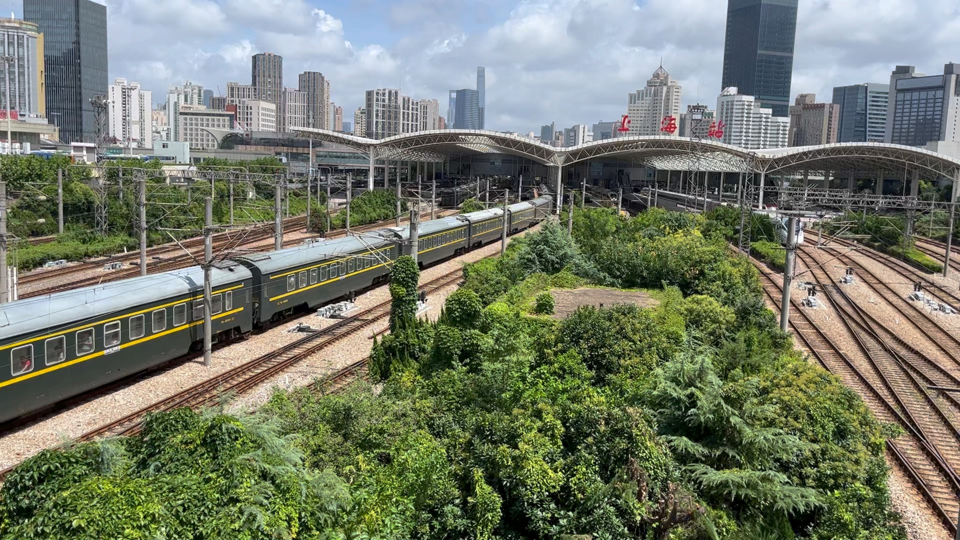 一辆用绿皮车厢的25t直达特快列车和旁边的高铁一同进入上海火车站