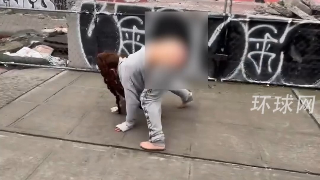 美国西雅图一女子在大街上衣衫不整、行为怪异：裤子半坠在腿上，手脚并用在地上爬行