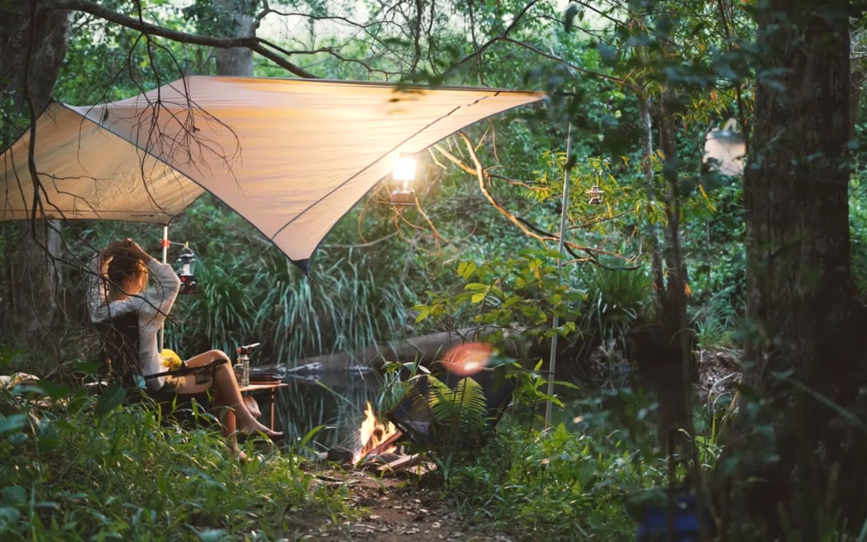 美女在森林溪水中露营喝啤酒吃烧烤聆听潺潺的溪水声