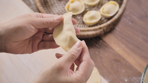 在饺子皮上放一勺馅,直接封口成半月形,再将两端折过来黏在一起,完成