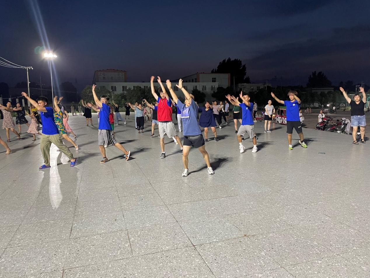 图为大学生社会服务团志愿者与当地村民一同跳广场舞.