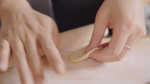 拇指放在中间,右手拿一个比较小的擀面杖,擀一下转一下就能擀成饺子皮